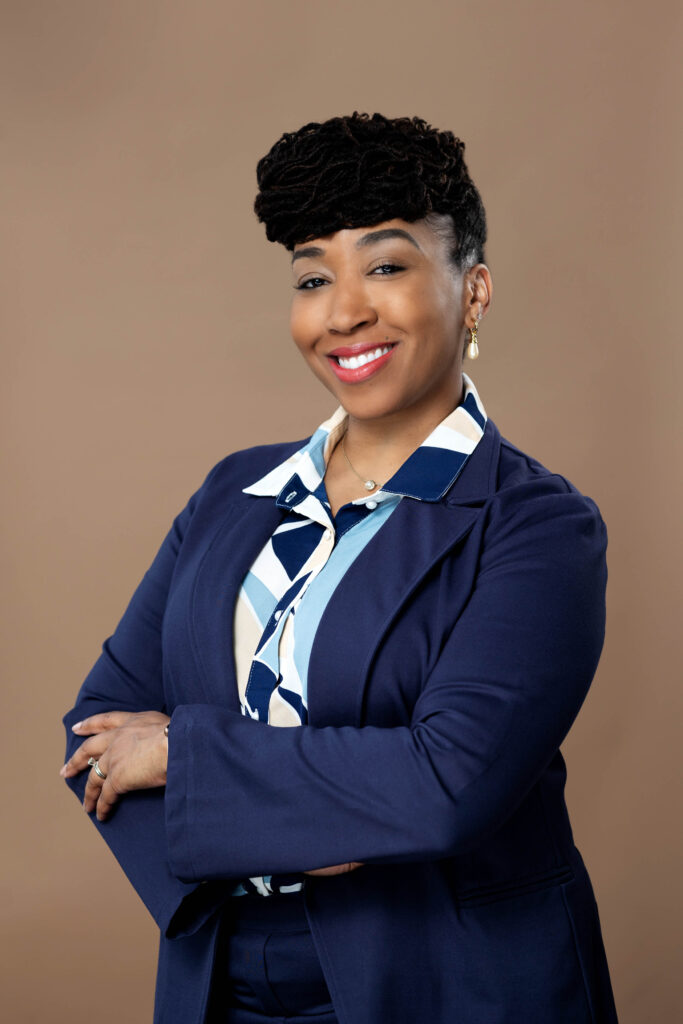 detroit woman headshot in a blue suit with bold design on her blouse with arms folded for LinkedIn profule